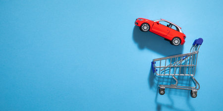 Toy red car with a shopping cart on the blue background.
