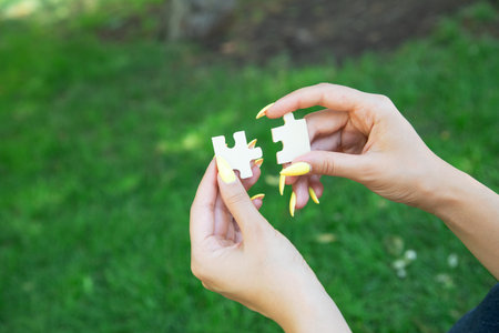 Woman holding a piece of wooden jigsaw puzzle together in the outdoors.