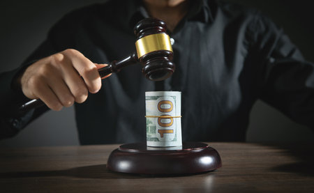 Male hand holding Judge gavel over money on wooden table.の写真素材