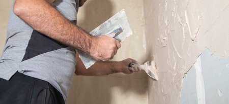 Man is applying putty on a wall. Renovating houseの写真素材