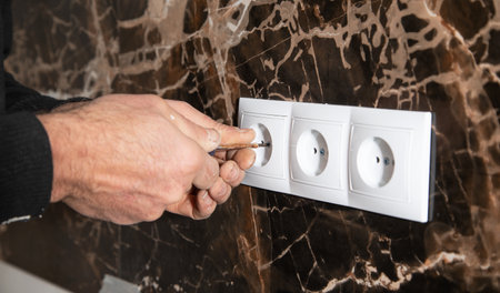 Electrician installing a wall socket at home.