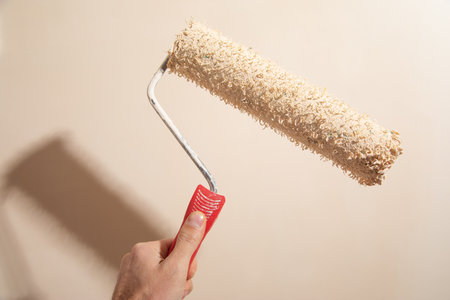 Male hand painting wall with paint roller.