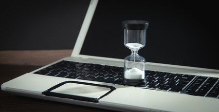 Hourglass on the laptop keyboard. time management. business