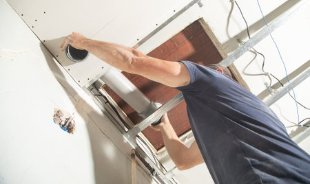 Worker repairing plastic chimney pipe at home.の写真素材