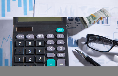 Pen, calculator, eyeglasses on financial graphs.の写真素材