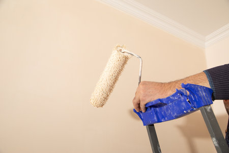 Male hand painting wall with paint roller.の写真素材