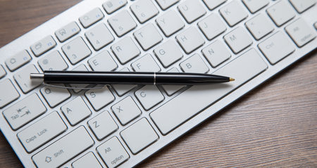 Black pen on the computer keyboard.の写真素材