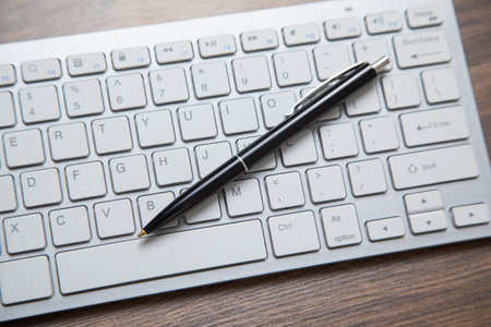 Black pen on the computer keyboard.の写真素材