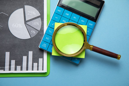 Magnifying glass with a sticky note on financial graphs.の写真素材
