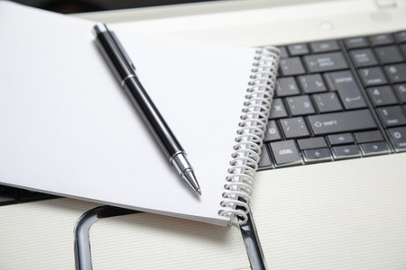 Pen and notepad on the computer keyboard.の写真素材