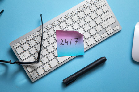 24/7 on sticky note with a computer keyboard.の写真素材