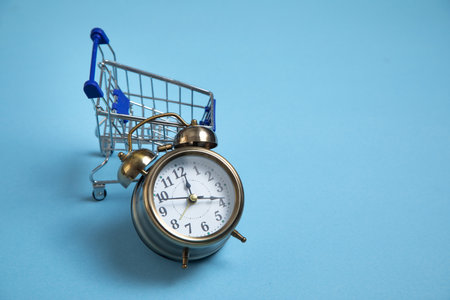 Alarm clock, shopping cart on the blue background.の写真素材