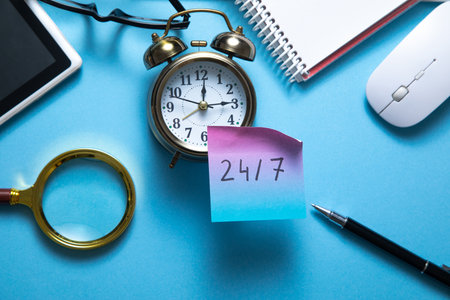 24/7 on sticky note with a alarm clock and business objects.の写真素材