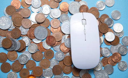 Computer mouse and coins on the blue background.の写真素材