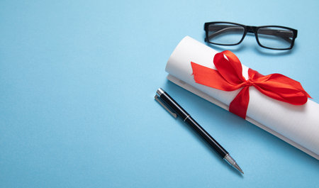 Diploma, eyeglasses, pen on the blue background.の写真素材