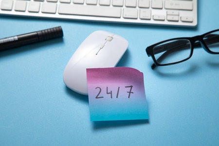 24/7 on sticky note with a computer keyboard.の写真素材