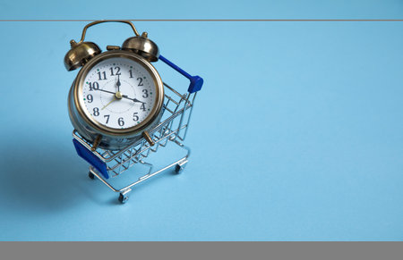 Alarm clock, shopping cart on the blue background.の写真素材