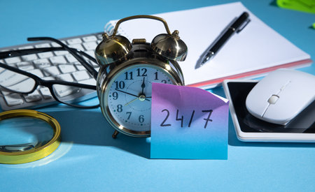 24/7 on sticky note with a alarm clock and business objects.の写真素材