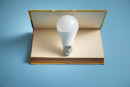 Light bulb and book on the blue background. Knowledge and wisdomの写真素材