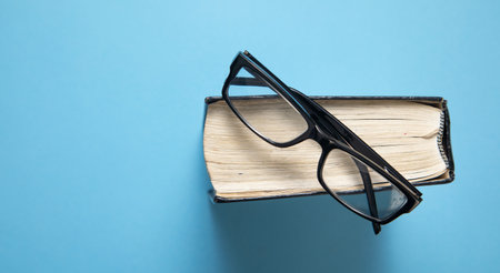 Eyeglasses and book on the blue background.の写真素材