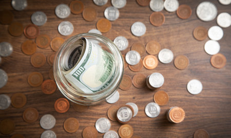 Jar of coins and dollars on wooden background.の写真素材