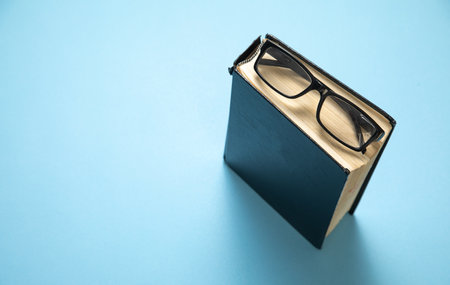 Eyeglasses and book on the blue background.の写真素材