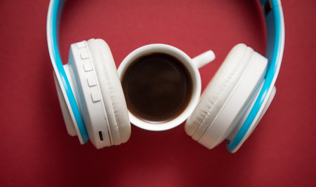 Coffee cup and headphones on the bordeaux background.の写真素材