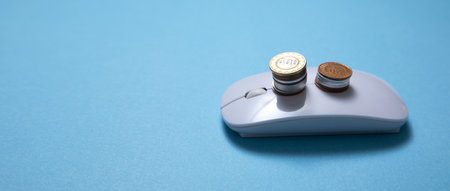 Computer mouse and coins on the blue background.の写真素材