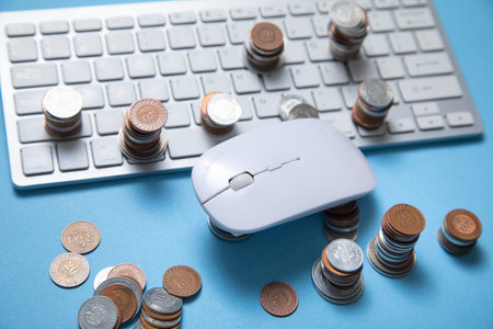 Computer mouse and coins on the blue background.の写真素材