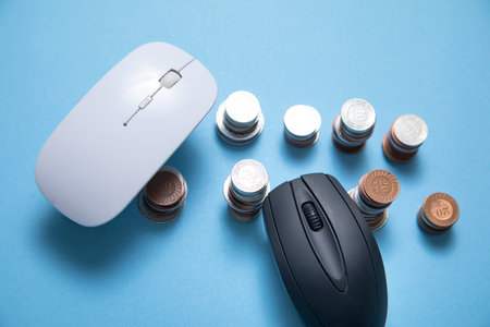 Computer mouse and coins on the blue background.の写真素材