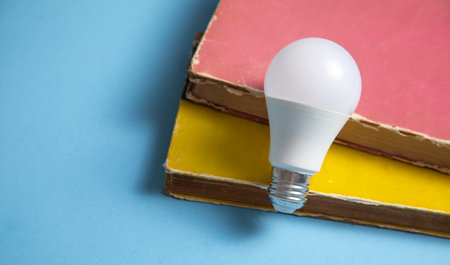 Light bulb and book on the blue background. Knowledge and wisdom