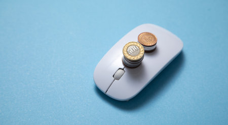 Computer mouse and coins on the blue background.の写真素材