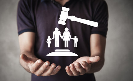 Male hand holding judge gavel with a family symbol. family lawの写真素材