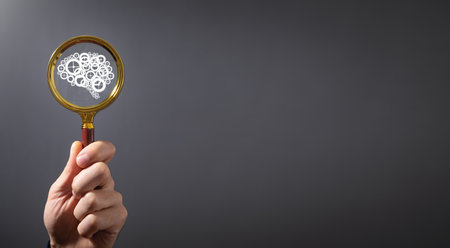 Male hand showing magnifying glass with a human brain.