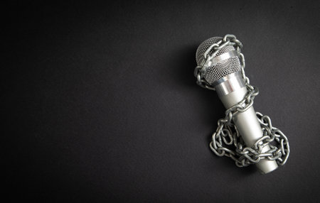 Microphone tied with chains on the black background.