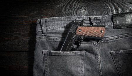 Pistol on jeans pocket on the dark background.の写真素材