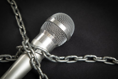 Microphone tied with chains on the black background.の写真素材
