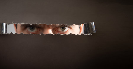 Man looking through hole in paper.