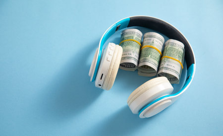 Headphones with a dollar money on the blue background.