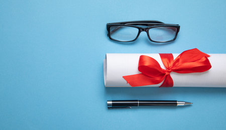 Diploma, eyeglasses, pen on the blue background.の写真素材