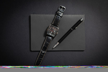 Black pen, wristwatch, notepad on the black background.の写真素材