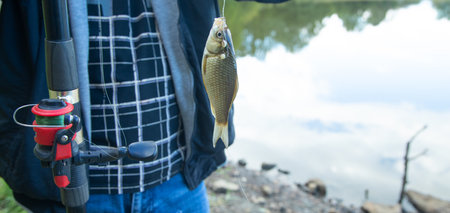 Man catching and showing small fish in the lake.