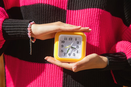 Caucasian young woman holding a clock.の写真素材