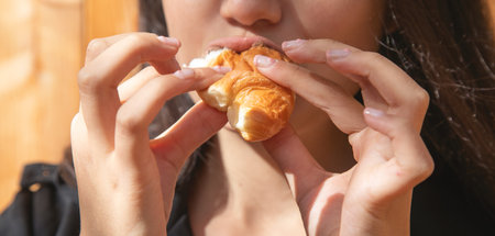 Young caucasian woman eating croissant.の写真素材