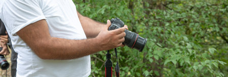 Man holding dslr camera in outdoor.
