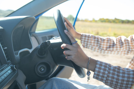 Female hands in steering wheel of car.