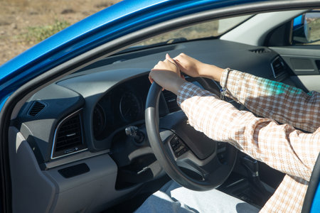 Female hands in steering wheel of car.の写真素材