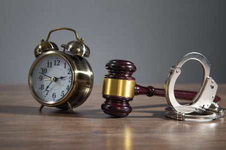 Handcuffs and alarm clock on the wooden background.の写真素材
