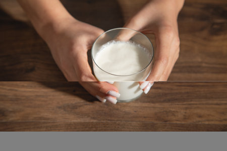 Hand holding a glass of milk on the table.の写真素材