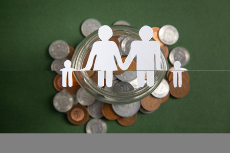 Paper family with a coins on the green background.の写真素材